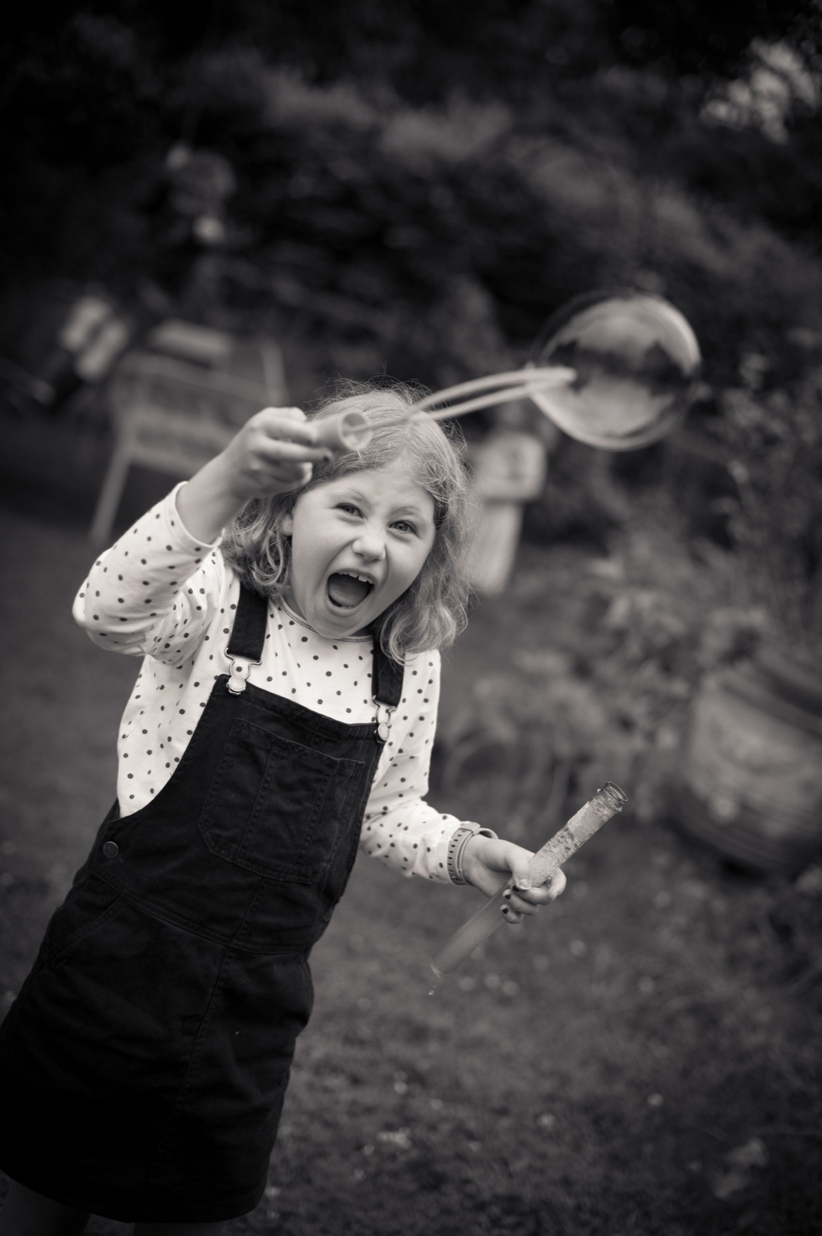Child laughing while blowing bubbles in a garden