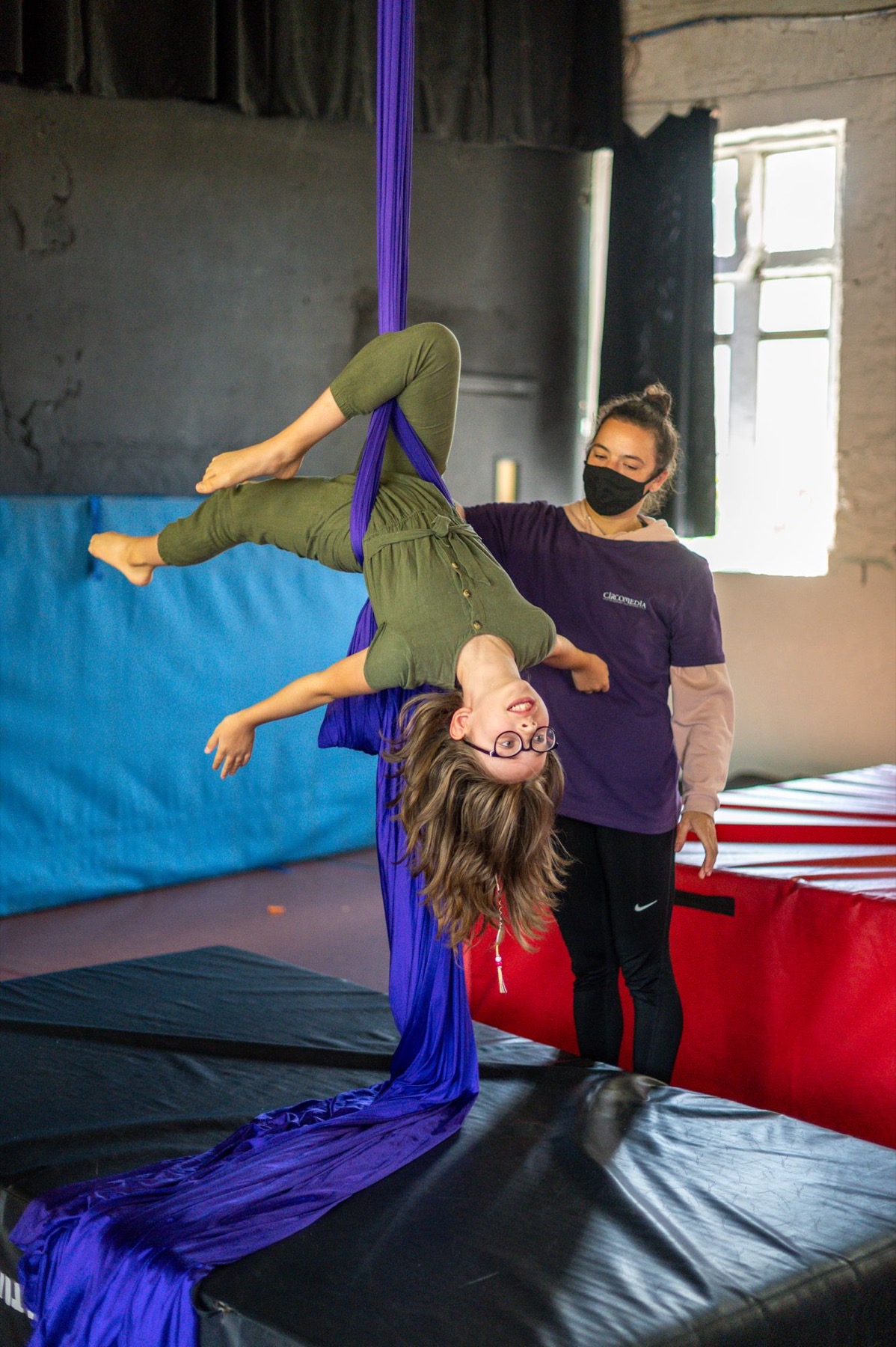 Child hanging upside down during a circus skills session