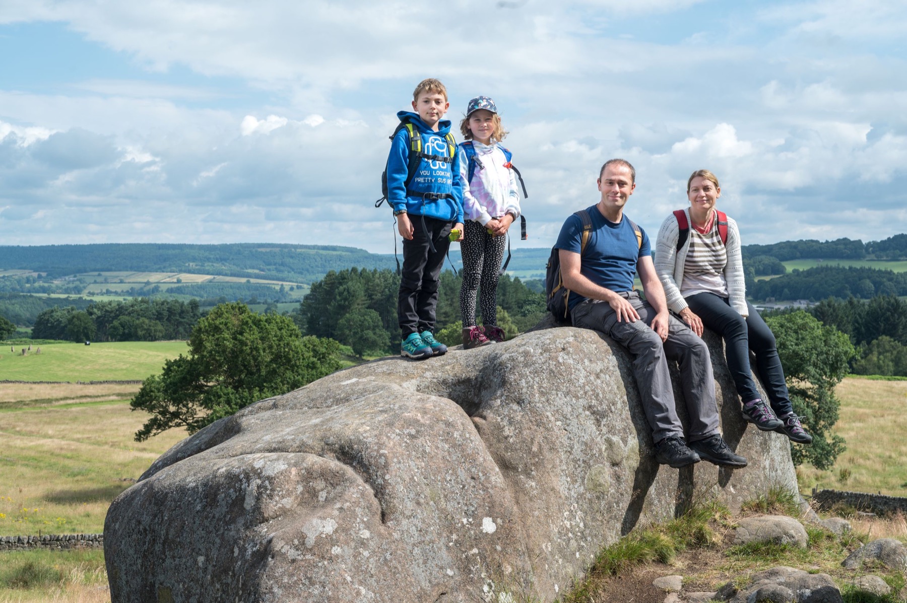 Family sitting together on rocks with a countryside view